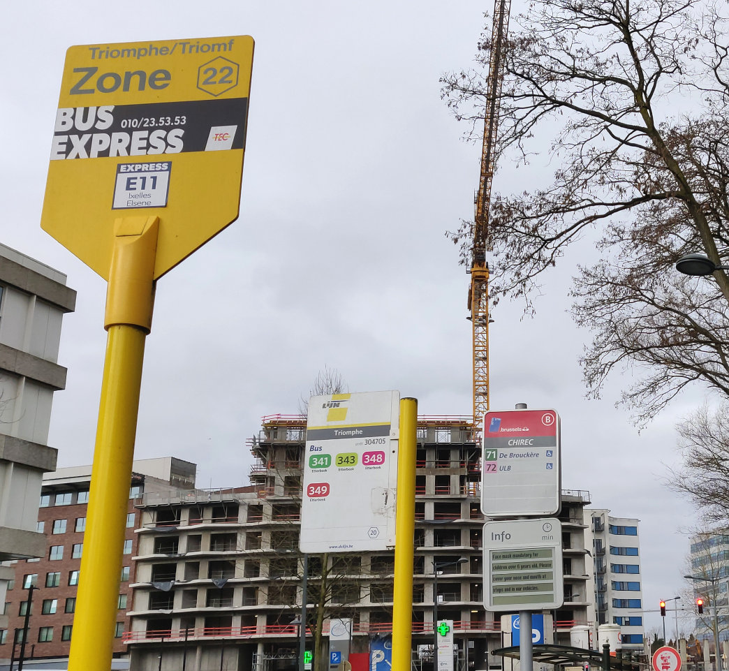 A bus stop sign in Brussels with 3 operators, each posting a sign with a different name